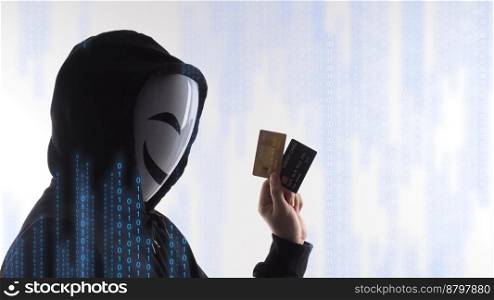 Hacker man and credit cards in hand. Represent credit cards personal data stolen by anonymous man in Black hood shirt. Credit cards data security and Cyber crime digital. Money transection unsecured.