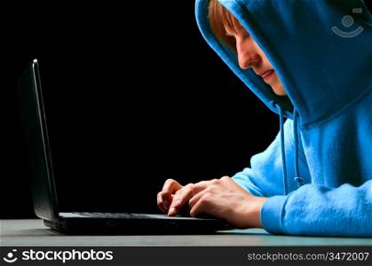 hacker. Young man is typing on laptop and looking at screen