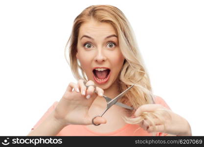 hair care, hairstyle and people concept - young woman or teenage girl with scissors cutting ends of her hair