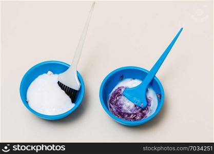 Hair dyeing at home or in hairdresser salon concept. Two blue plastic bowls with bleach, hair dye and brush. Two plastic bowls with bleach hair dye