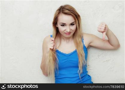 Hair problem. Blond woman teenage girl holding her damaged dry hair showing thumb down hand sign gesture. Indoor.