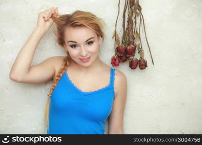 Hair problem. Blond woman teenage girl showing her damaged dry hair standing by bunch of dried roses flowers. Indoor.