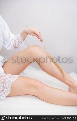 Hair removal, cosmetic body care concept. Beautiful soft skin, woman&rsquo;s legs with perfect skin, woman&rsquo;s hand touches the leg with a fluffy branch. Hair removal, cosmetic body care concept. Beautiful soft skin, woman&rsquo;s legs with perfect skin, woman&rsquo;s hand touches the leg with a fluffy branch.