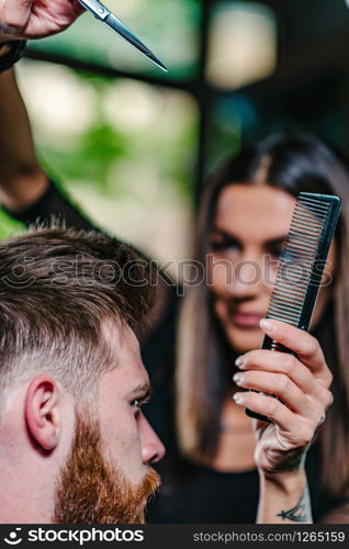 Hair styling man in hairsalon by female hairdresser