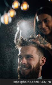 Hair styling man in hairsalon by female hairdresser