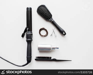 hair tools and hairdressing concept - curling iron, brushes, hot styling spay, ties and clips on white background. iron, brushes, styling spay, hair ties and pins