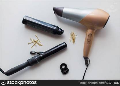 hair tools and hairdressing concept - hairdryer, hot styler or curling iron, styling spray, pins and hair ties on white background. hairdryer, styler or curling iron and hair spray