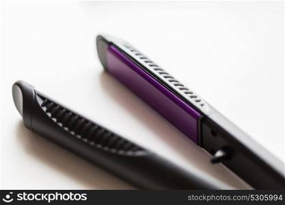 hair tools, beauty and hairdressing concept - close up of flat straightening iron on white background. close up of flat hair straightening iron