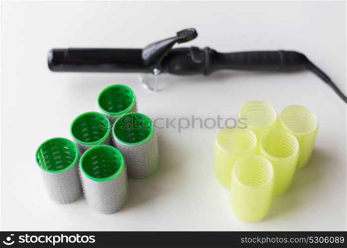 hair tools, beauty and hairdressing concept - curlers or rollers and iron or hot styler on white background. hair curlers or rollers and iron or hot styler