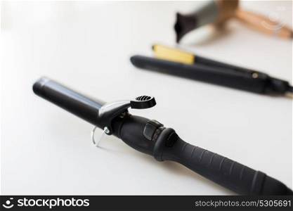 hair tools, beauty and hairdressing concept - curling iron, hot styler and hairdryer on white background. curling iron, hot styler and hairdryer