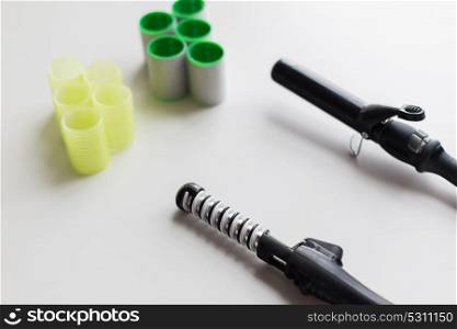 hair tools, beauty and hairdressing concept - curling irons or hot stylers and curlers on white background. curling irons or hot stylers and hair curlers