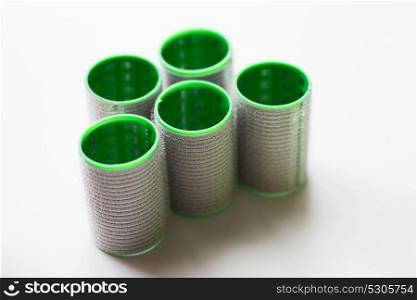hair tools, beauty and hairdressing concept - green curlers or rollers on white background. green hair curlers or rollers
