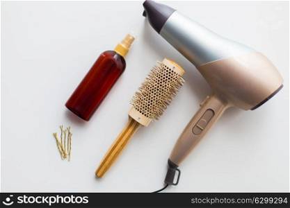 hair tools, beauty and hairdressing concept - hairdryer, brush, hot styling spray and pins on white background. hairdryer, brush, hot styling hair spray and pins