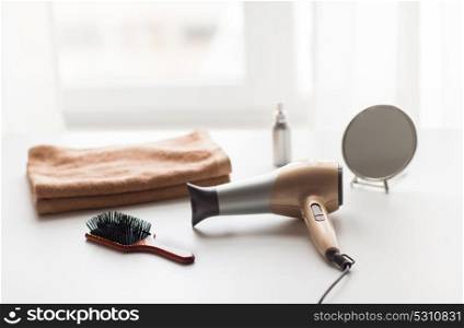 hair tools, beauty and hairdressing concept - hairdryer, brushes, mirror and towel on white background. hairdryer, hair brushes, mirror and towel
