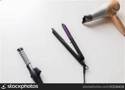 hair tools, beauty and hairdressing concept - hairdryer, hot styler and curling iron or tongs on white background. hairdryer, hot styler and curling iron or tongs