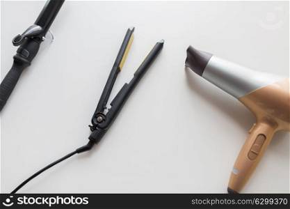 hair tools, beauty and hairdressing concept - hairdryer, hot styler and curling iron or tongs on white background. hairdryer, hot styler and curling iron or tongs