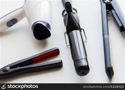 hair tools, beauty and hairdressing concept - hairdryer, hot styling and curling irons on white background. hairdryer, hot styling and curling irons