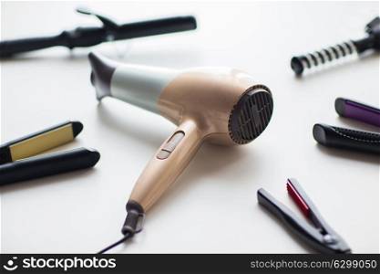 hair tools, beauty and hairdressing concept - hairdryer, hot styling and curling irons on white background. hairdryer, hot styling and curling irons