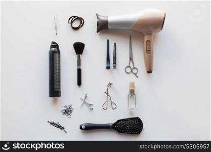 hair tools, beauty and hairdressing concept - hairdryer, scissors, comb and hot styling spay on white background. hairdryer, scissors and other hair styling tools