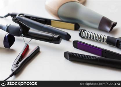 hair tools, beauty and hairdressing concept - hot styling and curling irons with hairdryers on white background. hot styling and curling irons with hairdryers