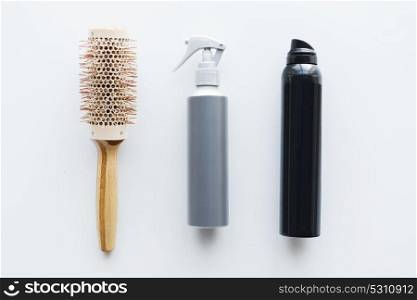 hair tools, beauty and hairdressing concept - hot styling sprays and curling brush on white background. styling hair sprays and curling brush