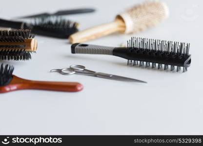 hair tools, beauty and hairdressing concept - scissors and different brushes on white background. scissors and different hair brushes
