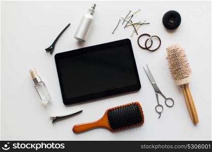 hair tools, beauty and hairdressing concept - tablet pc computer, scissors, brushes and styling sprays with pins and ties on white background. tablet pc, scissors, brushes and other hair tools