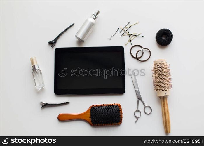 hair tools, beauty and hairdressing concept - tablet pc computer, scissors, brushes and styling sprays with pins and ties on white background. tablet pc, scissors, brushes and other hair tools