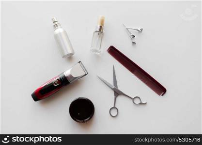 hair tools, hairstyle and hairdressing concept - styling spray, trimmer or clipper with scissors and comb on white background. styling hair spray, trimmer and scissors
