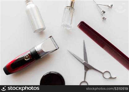 hair tools, hairstyle and hairdressing concept - styling spray, trimmer or clipper with scissors and comb on white background. styling hair spray, trimmer and scissors