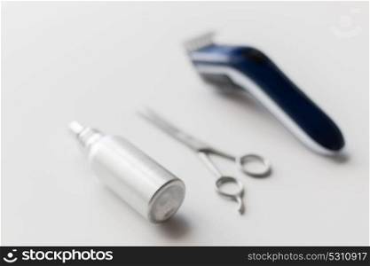 hair tools, hairstyle and hairdressing concept - styling spray, trimmer or clipper and scissors on white background. styling hair spray, trimmer and scissors