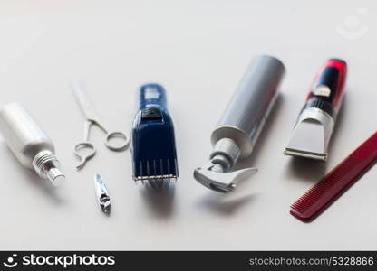 hair tools, hairstyle and hairdressing concept - styling sprays, trimmers or clippers with scissors and comb on white background. styling hair sprays, clippers, comb and scissors