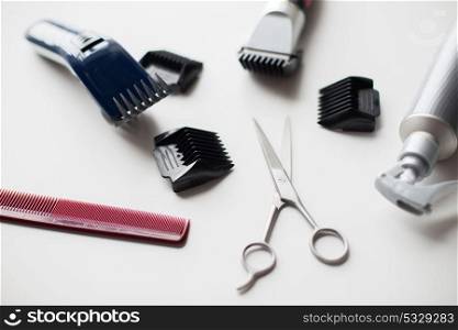 hair tools, hairstyle and hairdressing concept - styling sprays, trimmers or clippers with scissors and attachment combs on white background. styling hair sprays, clippers, comb and scissors