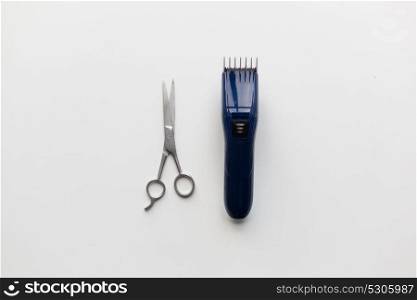 hair tools, hairstyle and hairdressing concept - trimmer or clipper and scissors on white background. hair trimmer and scissors on white background