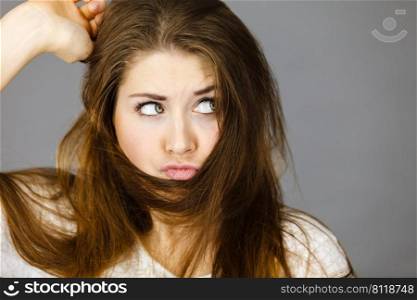 Haircare and hairstyling concept. Woman having face covered with her dark brown hair being confused. Woman having face covered with her brown hair