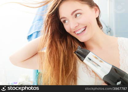 Haircare. Beautiful long haired woman drying hair in bathroom