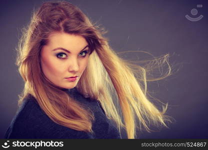 Haircare, beauty, hairstyling concept. Portrait of young attractive blonde woman wearing dark t shirt having windblown beautiful long hair.. Attractive blonde woman with windblown hair