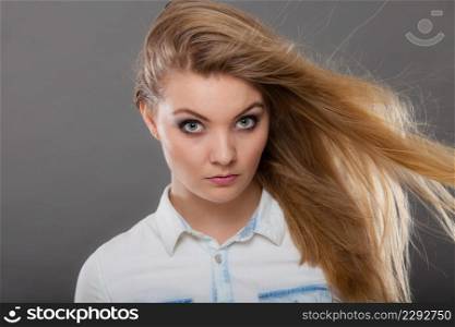 Haircare, beauty, hairstyling concept. Portrait of young attractive blonde woman wearing white shirt having windblown beautiful long hair.. Attractive blonde woman with windblown hair