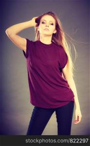 Haircare, beauty, hairstyling concept. Portrait of young attractive brunette woman wearing dark tshirt holding her beautiful long brown hair.. Attractive brunette woman with windblown hair