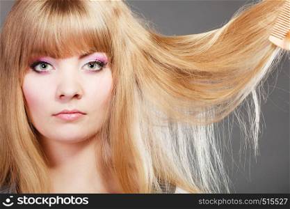 Haircare. Blonde woman with her damaged dry hair serious face expression gray background