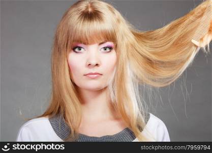 Haircare. Blonde woman with her damaged dry hair serious face expression gray background