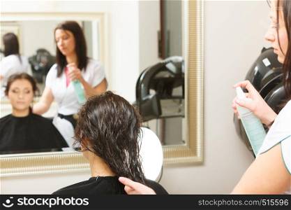 Haircare, relaxation and hairstyling concept. Woman sitting in black cape getting her hair cut by lady hairdresser in beauty salon. Woman getting hair cut in a beauty salon