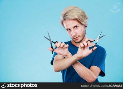 Haircut coiffure haircare concept. Passionate male hairdresser holding scissors showing work tools normal and thinning shears. Man with scissors for haircutting