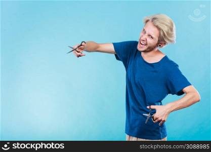 Haircut coiffure haircare concept. Passionate male hairdresser holding scissors showing work tools normal and thinning shears. Man with scissors for haircutting