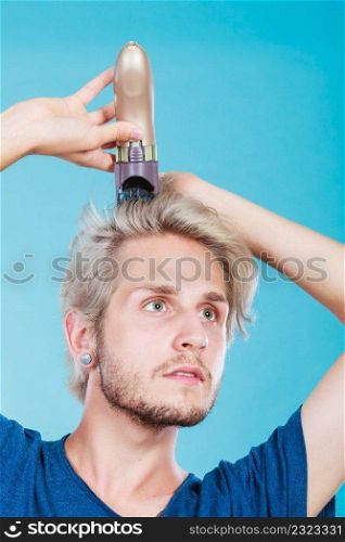 Hairdo hairstyle concept. Cool male hairstylist making self trendy haircut, fashion blonde metrosexual model going to shave his long hair. Man going to shave his long hair