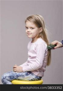 Hairdresser brushing her long hair five year old girl