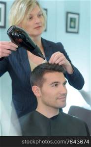 Hairdresser drying male customer's hair