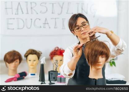 Hairdresser educator with students, explaining hair cutting technique on mannequin head for training. Hairdresser Educator with Students, Explaining Hair Cutting Technique on Mannequin Head for Training