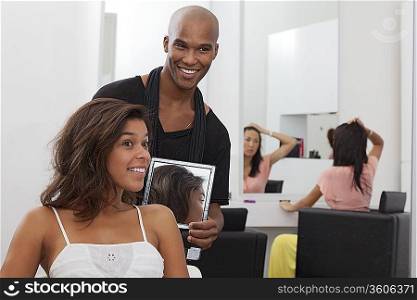 Hairdresser holding a mirror behind young woman
