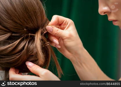 Hairdresser makes hairstyles for a young woman in beauty salon close up. Hairdresser makes hairstyles for a young woman in beauty salon close up.